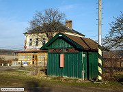 Budova starých dřevěných záchodů v železniční stanici Mníšek pod Brdy. V pozadí snímku je vidět budova restaurace, která byly oblíbená mezi řadou zdejších výletníků, což ostatně platí dodnes. Foto z 31. března 2008.